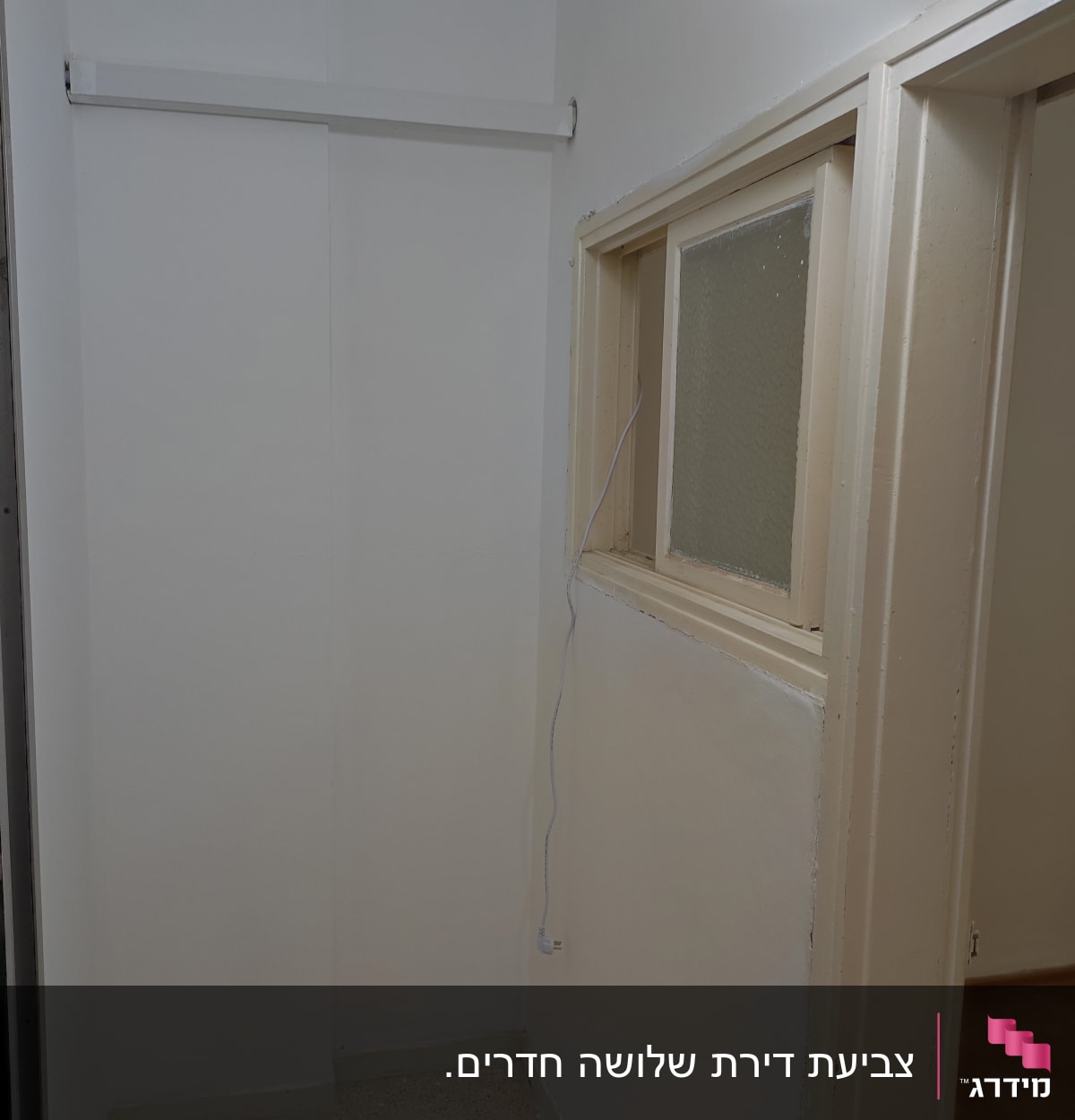 קיר צבוע בלבן עם חלון קטן ומנורה